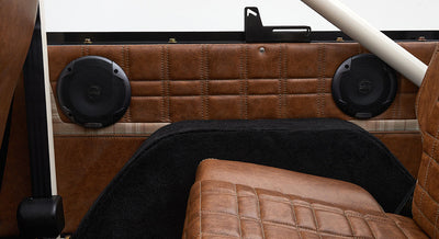 Rear side interior panel with two black speakers and brown leather trim in Classic Ford Bronco