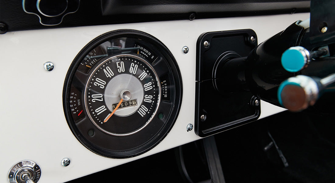 Classic Ford Bronco speedometer and fuel gauge on white dashboard with steering column