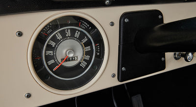 Classic Ford Bronco dashboard speedometer with white face and red needle