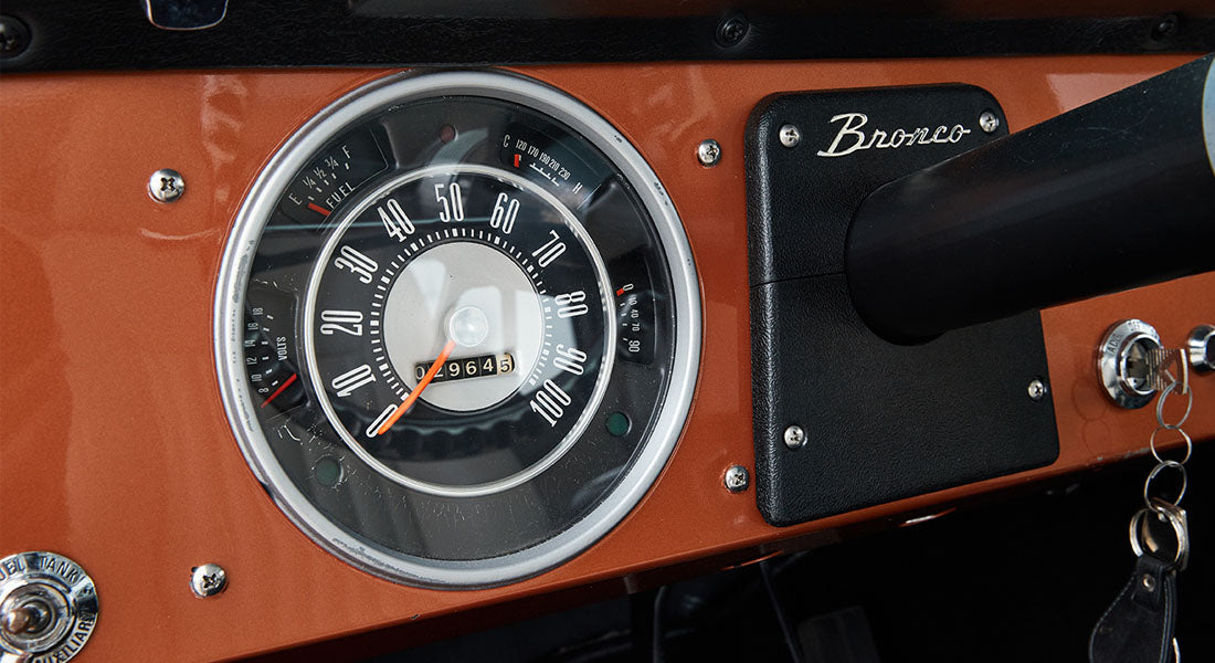 Classic Ford Bronco speedometer with black bezel and orange dashboard panel