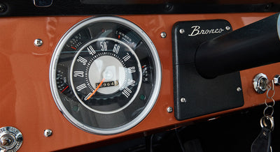 Classic Ford Bronco speedometer with black bezel and orange dashboard panel
