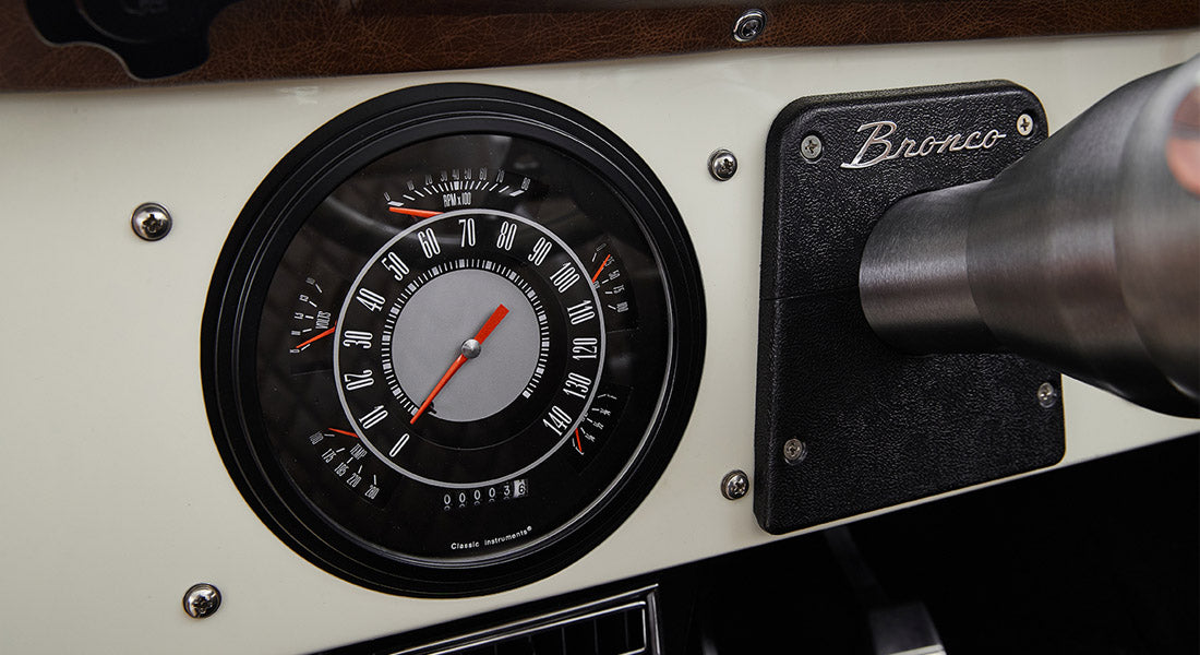 Classic Ford Bronco speedometer and tachometer with adjacent Bronco nameplate on dashboard