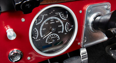 Classic Ford Bronco black gauge cluster with speedometer, fuel, temperature, oil and volts gauges on red dashboard