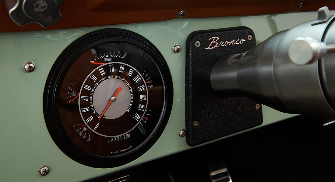 Dashboard speedometer and tachometer of a Classic Ford Bronco with mint green dash and black casing.