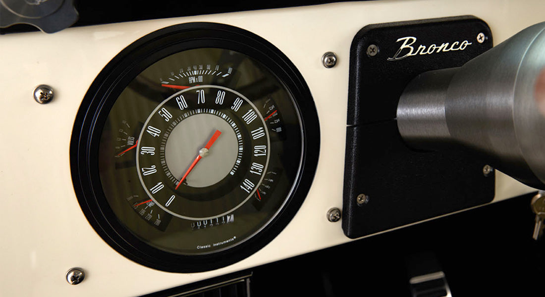 Classic Ford Bronco speedometer and gauges on white dashboard with Bronco script nameplate