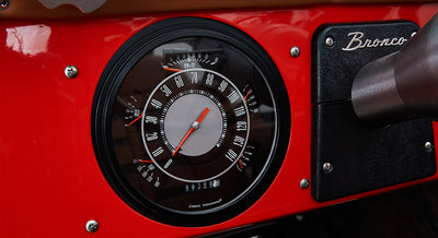 Classic Ford Bronco dashboard with round speedometer and red panel