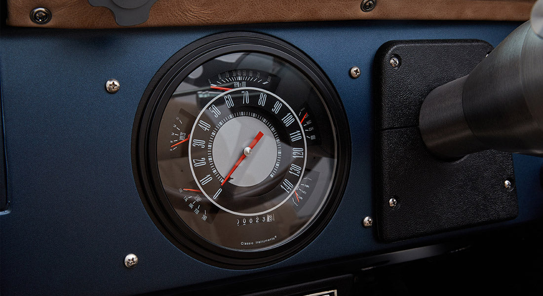 Classic round speedometer with black bezel and white numbers on a blue dashboard