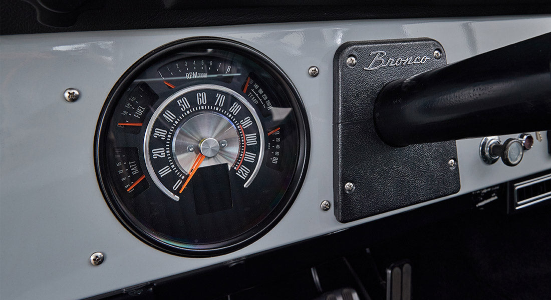 Classic Ford Bronco dashboard speedometer showing speed up to 120 mph with 'Bronco' script plate to the right