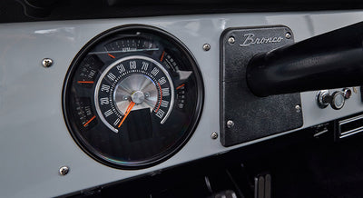 Classic Ford Bronco dashboard speedometer showing speed up to 120 mph with 'Bronco' script plate to the right