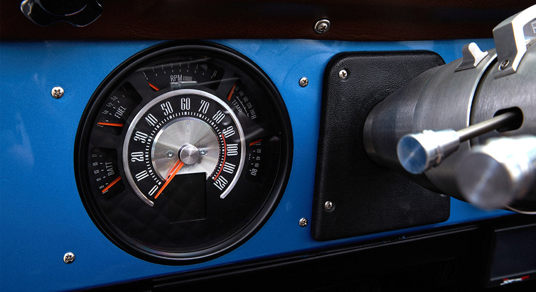 Classic Ford Bronco dashboard speedometer showing speed up to 120 mph with surrounding gauges.