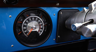 Classic Ford Bronco dashboard speedometer showing speed up to 120 mph with surrounding gauges.