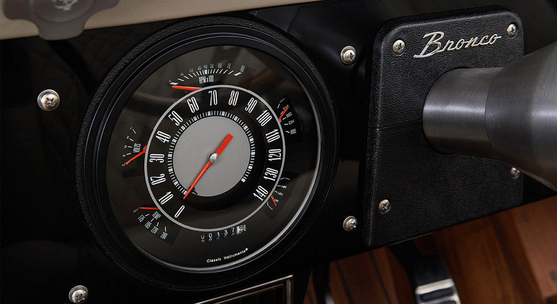 Classic Ford Bronco dashboard showing speedometer and tachometer with Bronco branding on steering column