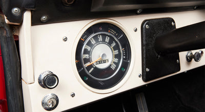 Classic Ford Bronco dashboard showing speedometer gauge and control knobs in black and white interior.