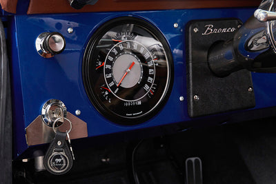 Blue dashboard panel of Classic Ford Bronco with speedometer and ignition key with Bronco keychain