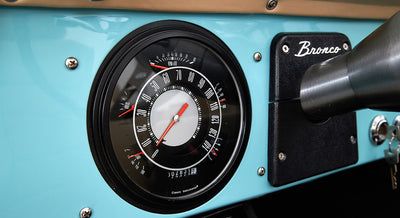 Classic Ford Bronco dashboard with speedometer and tachometer on light blue panel