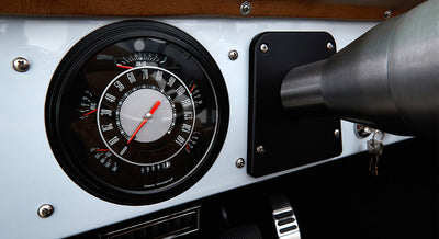 Classic Ford Bronco dashboard with round speedometer and odometer set in white and black panel.