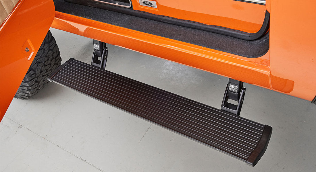 Retractable black step mounted below orange vehicle door opening