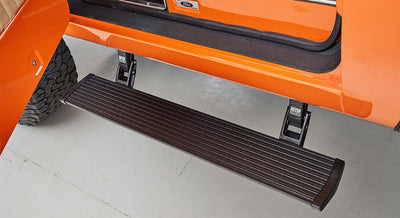 Retractable black step mounted below orange vehicle door opening