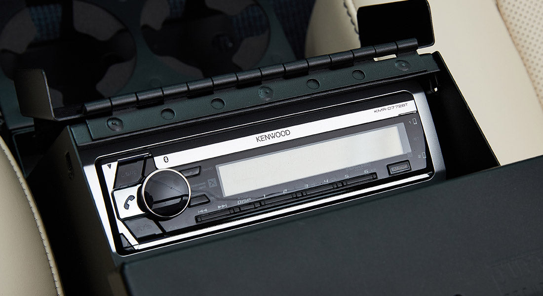 Kenwood stereo unit installed in black compartment with beige upholstery surrounding