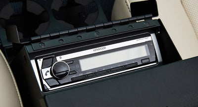 Kenwood stereo unit installed in black compartment with beige upholstery surrounding