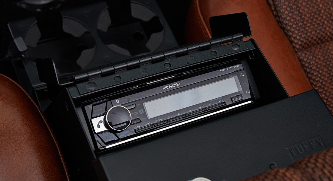 Kenwood stereo system installed in center console between brown leather seats.