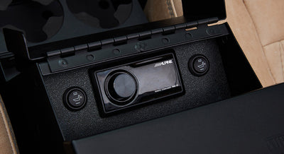 Close-up of Alpine car stereo controls with heated seat buttons on tan leather background