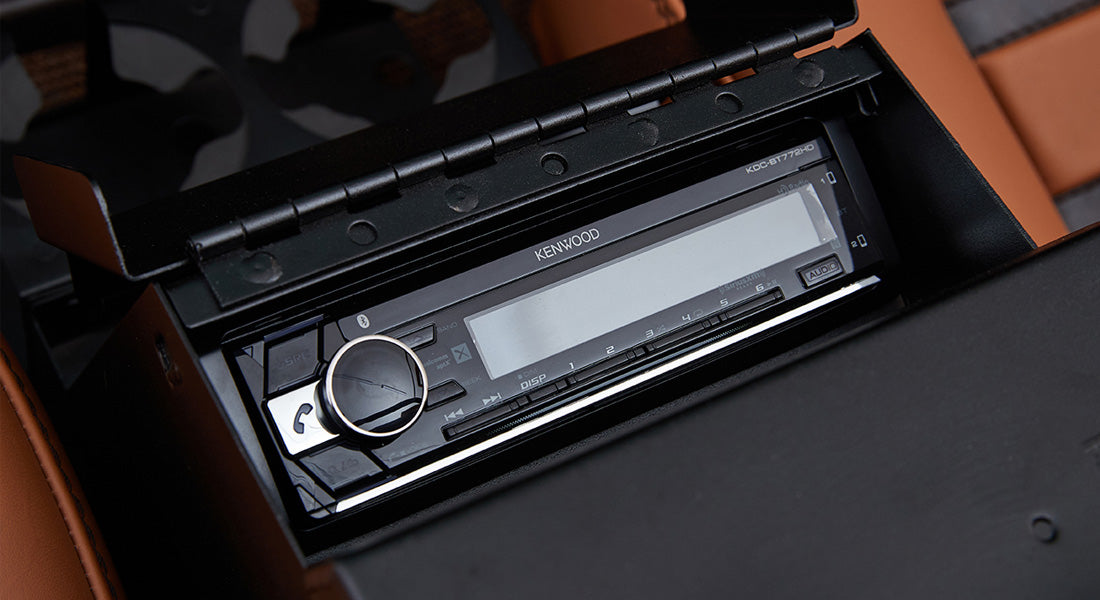 Black Kenwood stereo installed in Classic Ford Bronco center console with open lid