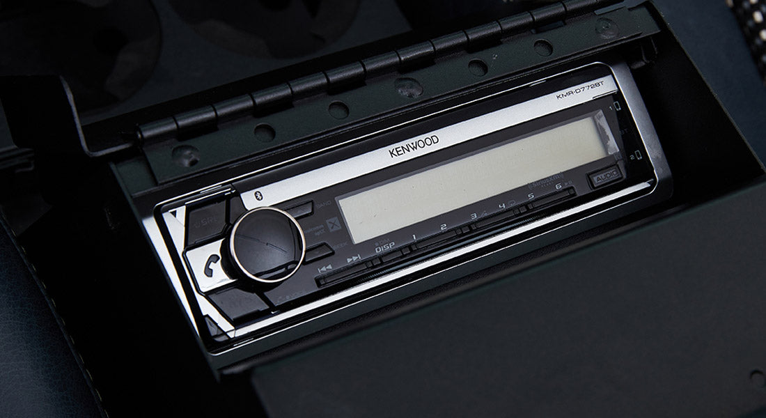 Car stereo branded Kenwood with turn dial and buttons installed in vehicle dashboard