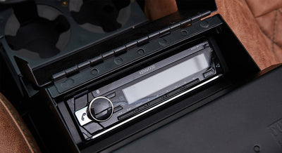 Car stereo console with Kenwood receiver and open lid on Classic Ford Bronco