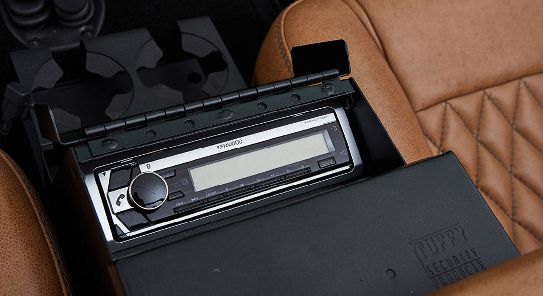 Kenwood stereo installed between brown quilted leather seats inside a Classic Ford Bronco