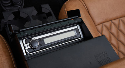 Kenwood stereo installed between brown quilted leather seats inside a Classic Ford Bronco