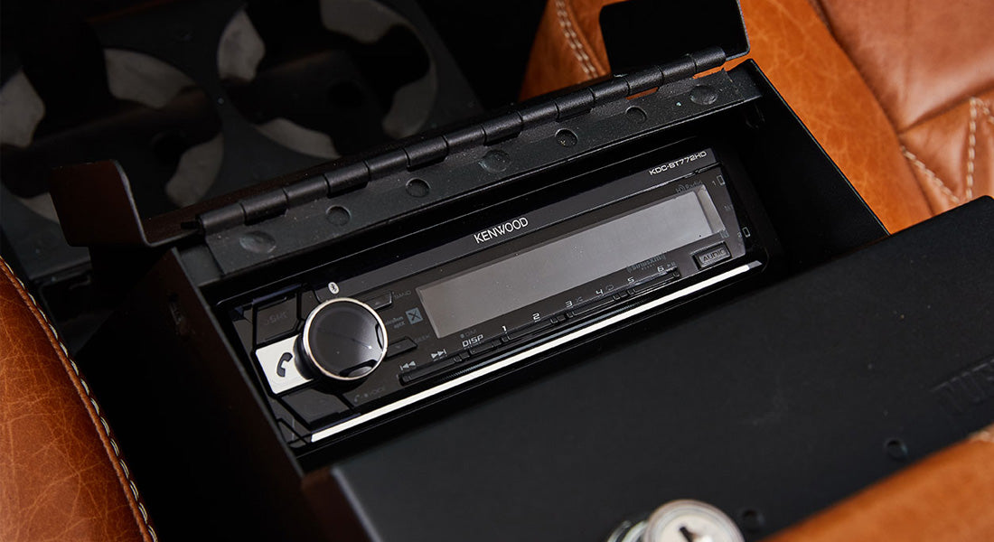 Black Kenwood stereo system installed in black console with brown leather surrounding