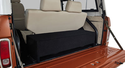 Open rear hatch of Classic Ford Bronco showing cream rear seats and black speaker box in cargo area