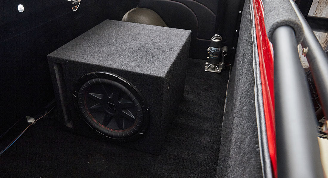 Large black subwoofer box installed in the rear cargo area of a Classic Ford Bronco