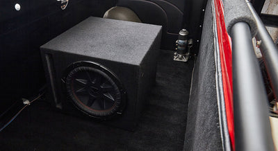 Large black subwoofer box installed in the rear cargo area of a Classic Ford Bronco