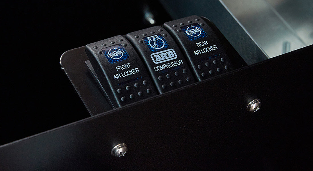 Black switches panel with labeled rocker switches for front air locker, ARB compressor, rear air locker