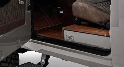 Open vehicle door showing detailed teak wood flooring and brown leather seat