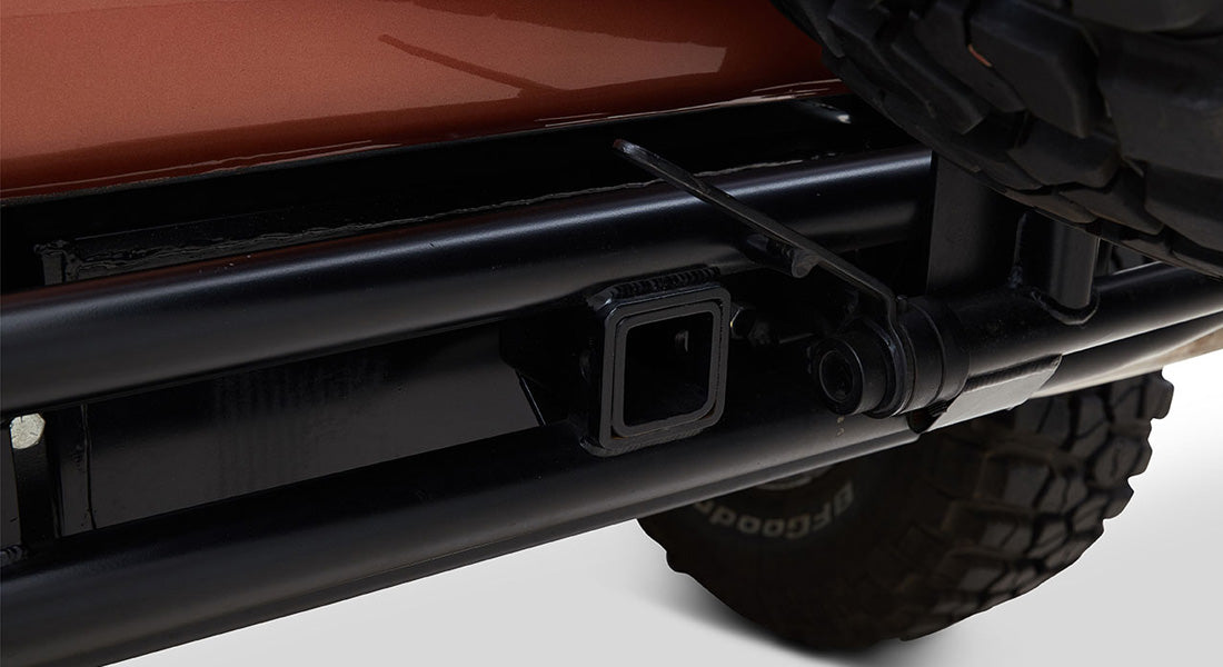 Close-up of black tow hitch and rear tire on Classic Ford Bronco with orange body