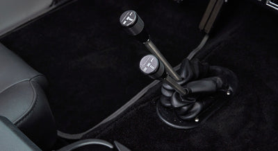 Two gear shift levers on black carpeted floor of Classic Ford Bronco interior