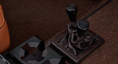 Two black gear shift levers with leather boots and cup holder in Classic Ford Bronco interior