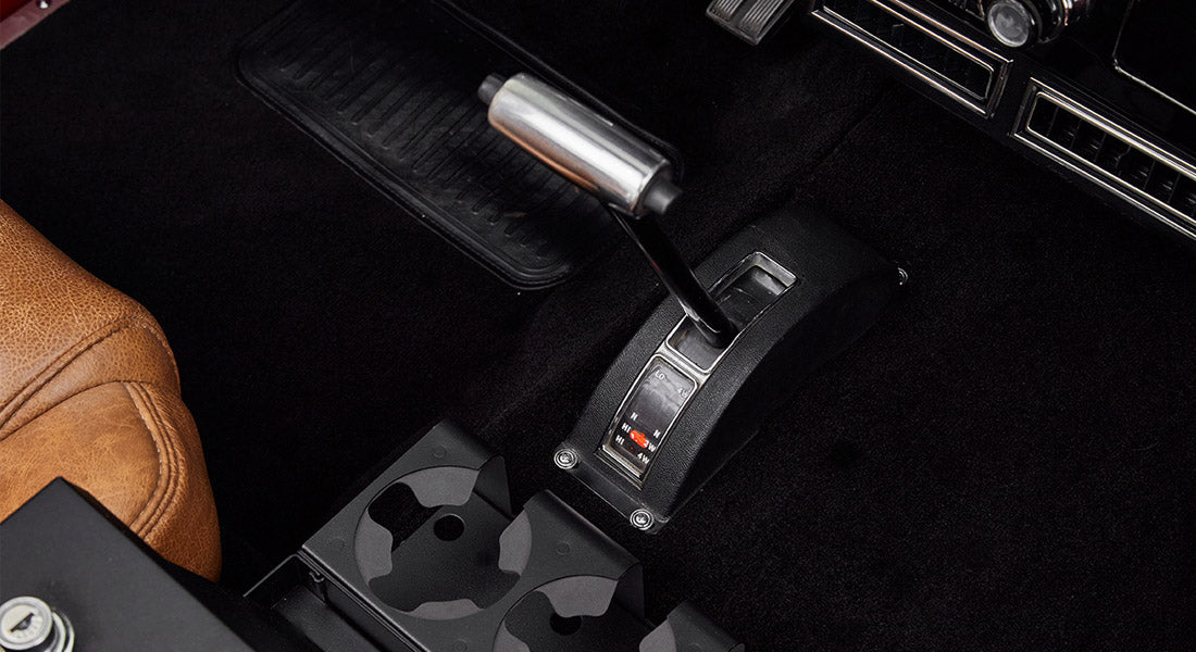 Transfer case lever and cup holders between brown leather seats in Classic Ford Bronco interior