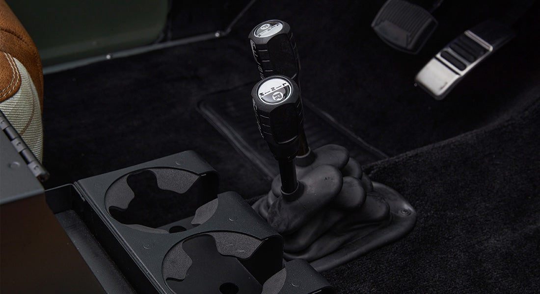 Gear shifters and cup holders shown on carpeted floor of Classic Ford Bronco interior