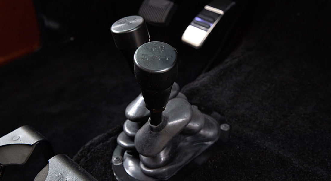 Two black knobs mounted on a metal base in the floor console