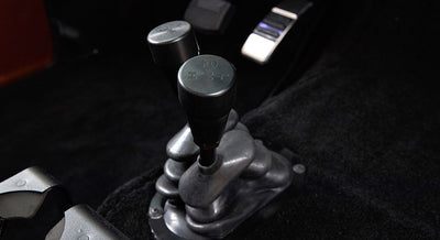 Two black knobs mounted on a metal base in the floor console