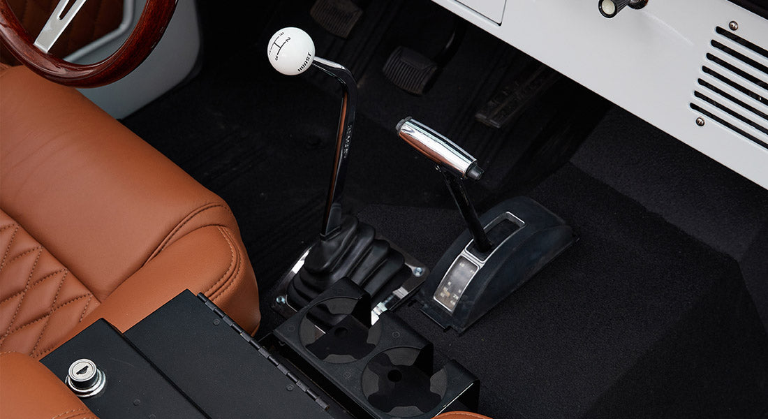 Classic Ford Bronco gear shifter and parking brake lever near tan leather seats