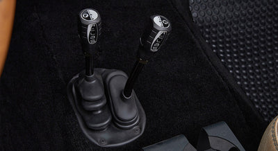 Two black transfer case shifters labeled Aellas with white icons on black carpet