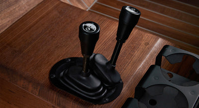 Two black gear levers mounted on wood floor next to black cup holders