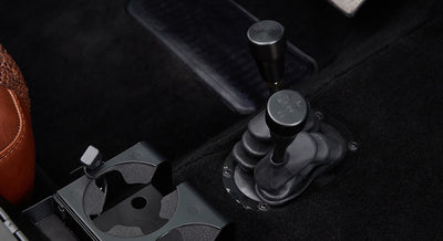 Gear shift levers and cup holders on carpeted floor of Classic Ford Bronco interior.