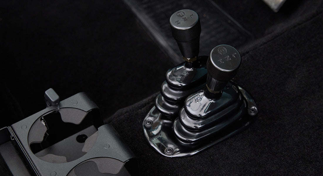 Two black gear shift levers on the floor of Classic Ford Bronco
