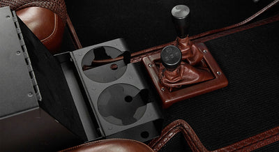 Classic Ford Bronco interior cup holder and two brown leather gear shifters with black carpet